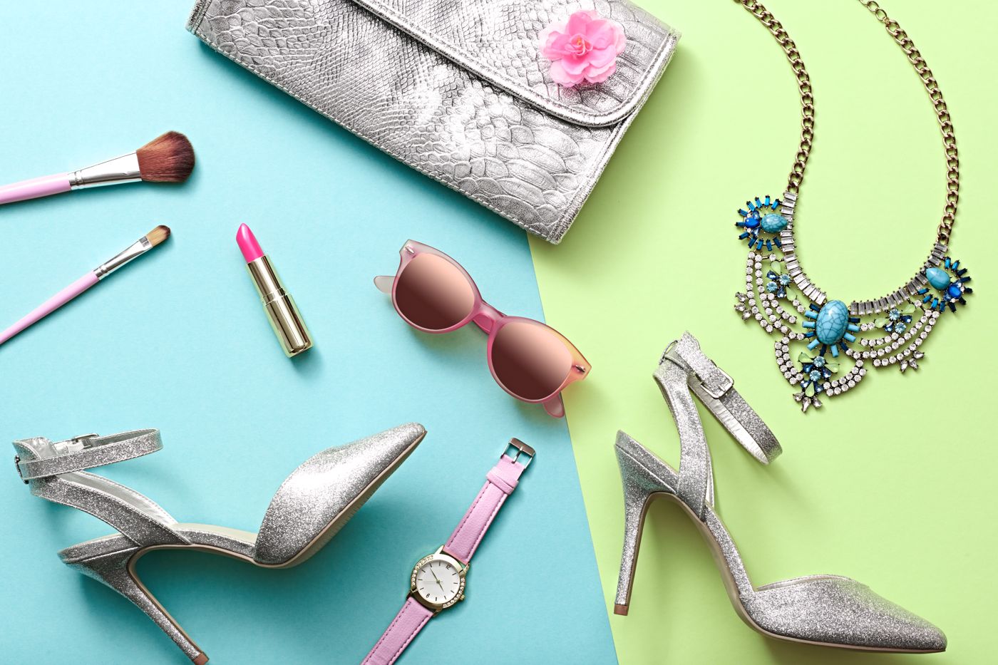 Flat lay of model accessories — heels, clutch, jewelry and sunglasses on pastel