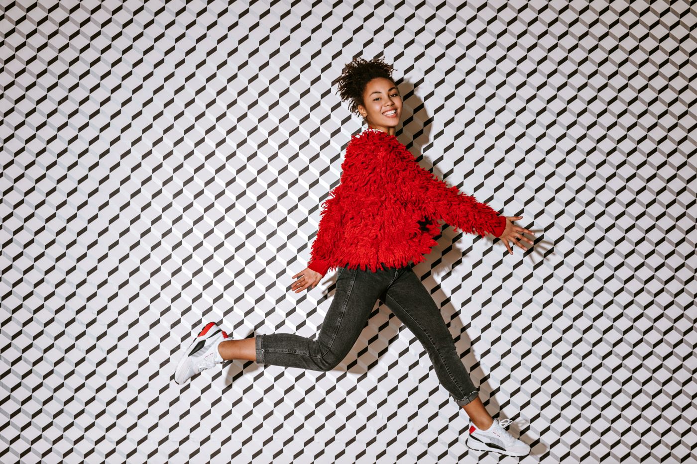 Model in a red jacket running against a textured wall